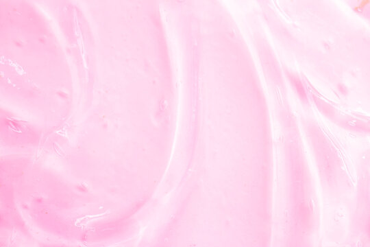 Cosmetic gel, serum, clear sample with a pink tint, close-up. Liquid cream with a foaming texture. Gel-like texture of a cosmetic product. Liquid cosmetic lotion for skin care.
