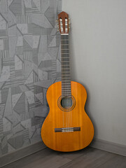 Naklejka premium Classical acoustic guitar standing in room corner soft daylight side view