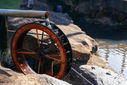 Rustic wooden water wheel operating in a traditional eco friendly hydraulic pumping system