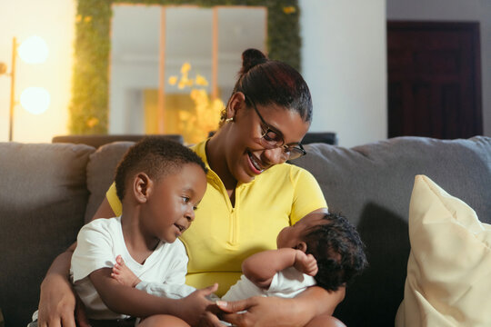 Mother holding newborn baby and older son at home