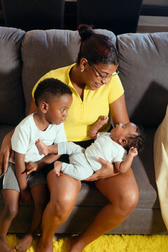 Mother embracing baby son with older child watching