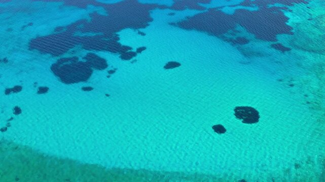 Overhead aerial drone view of the clear turquoise sea patterned with dark underwater reefs off Gramvousa island, Gramvousa, Greece