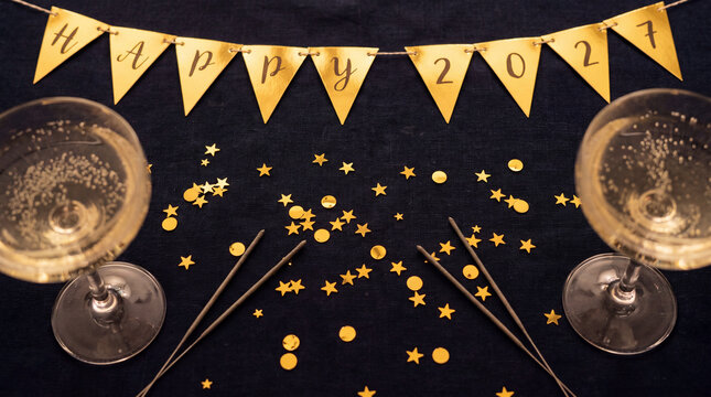 Champagne glasses with Happy 2027 banner and festive confetti on dark background