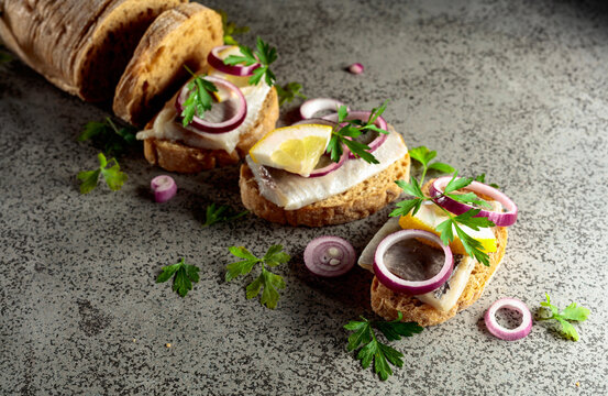Open sandwiches with herring filet, red onion, lemon, and parsley.