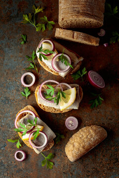 Open sandwiches with herring filet, red onion, lemon, and parsley.
