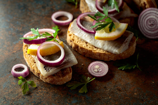 Open sandwiches with herring filet, red onion, lemon, and parsley.