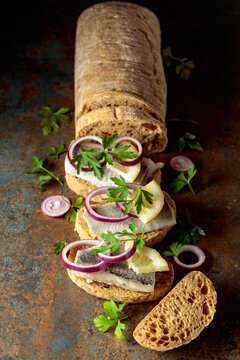 Open sandwiches with herring filet, red onion, lemon, and parsley.