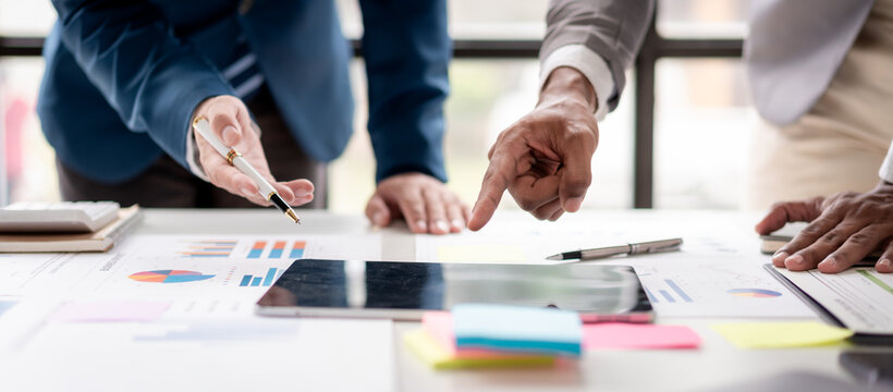 Three people are looking at a table with a lot of papers and a tablet