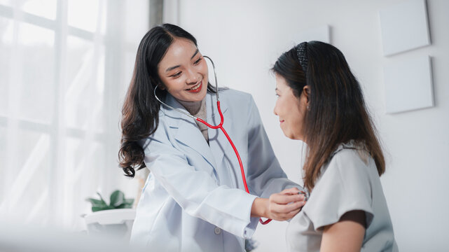 Asian Young Doctor Examining Adult Patient with Stethoscope in C