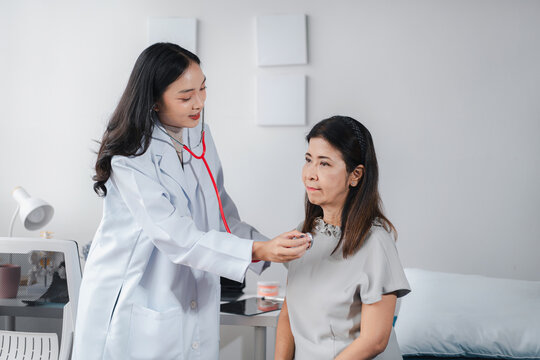Asian Young Doctor Examining Older Female Patient with Stethosco