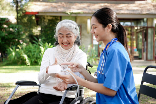 A woman in a blue shirt is helping an older woman with a blood p