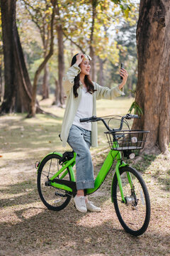 A woman is riding a green bike and taking a selfie