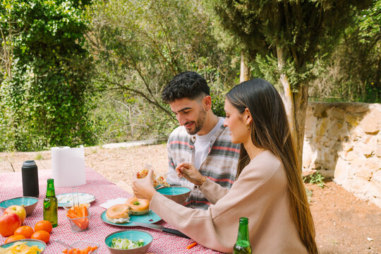 Couple sharing outdoor picnic lunch at forest table