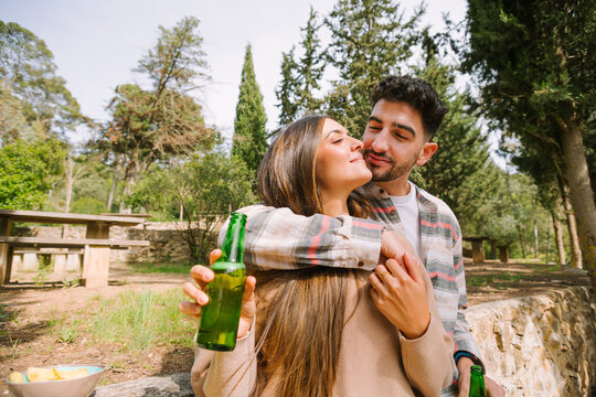 Romantic couple hugging at picnic with beer in park