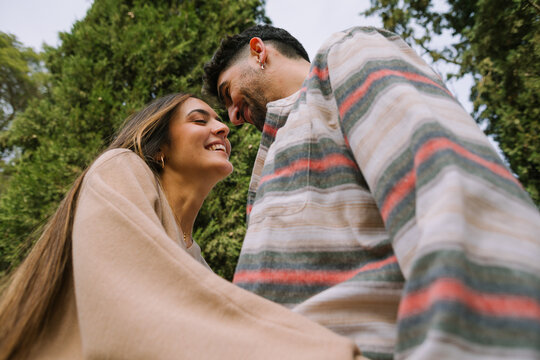 Young couple smiling and hugging outdoors in a green park