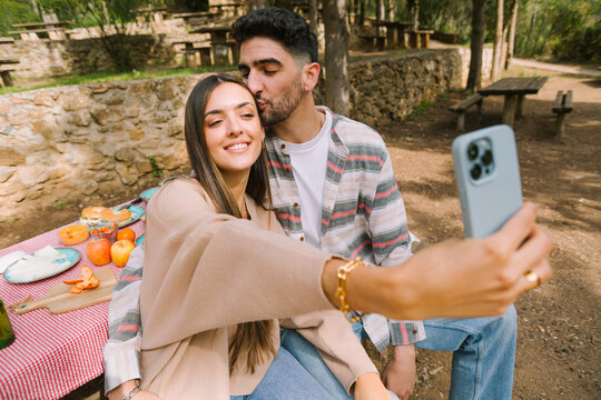 Couple taking selfie at picnic in park with affection