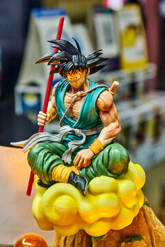 Ambato, Ecuador - October 28, 2025: Stylized Dragon Ball Z anime figurine protagonist Son Goku in sitting pose holding Power Pole staff, placed on top of yellow Kinto-un cloud prop in display setting.