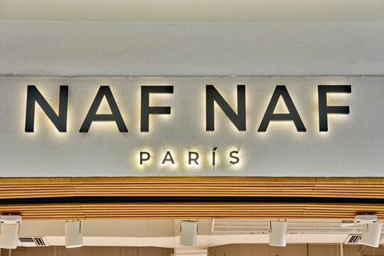 Ambato, Ecuador - October 28, 2025: NAF NAF Paris brand signage illuminated on a wall with wooden accents and modern lighting fixtures in a retail environment