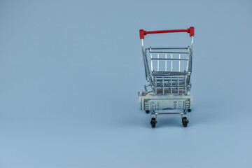 Mini shopping cart beside crumpled dollar bill © Nazir