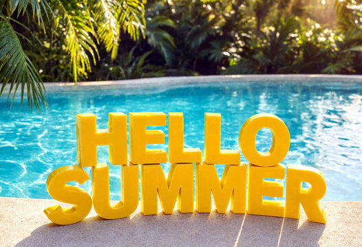 Bright yellow hello summer sign displayed by a swimming pool with tropical greenery around