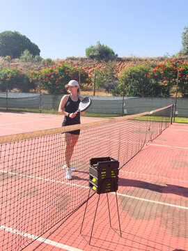 Active young woman trying to beat the ball by Padel racket while playing tennis in the court