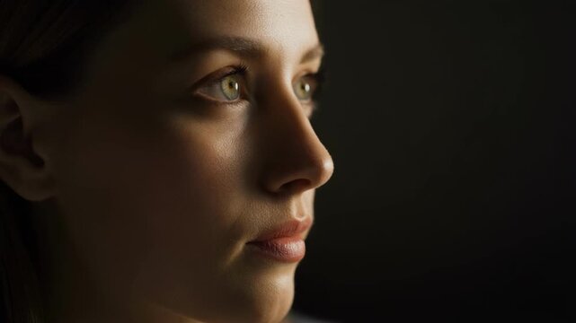 Woman's profile illuminated with dramatic chiaroscuro lighting during a contemplative moment