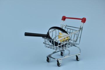 Mini shopping cart holds magnifying glass © Nazir