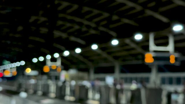 Blurred view of a train station platform with glowing lights and a dark ceiling structure