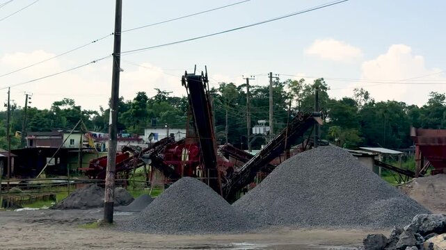 Industrial site with machinery and gravel piles under a blue sky with scattered clouds
