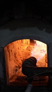 Vertical close-up of a traditional masonry bakery oven with gas burner and glowing refractory bricks