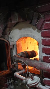Slow zoom out of a traditional masonry bakery oven with glowing refractory bricks and gas burner