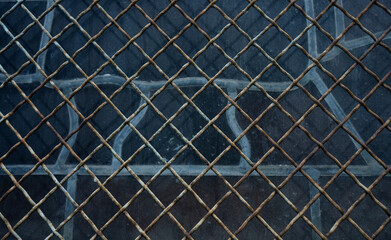 Fototapeta premium Full frame horizontal shot of rusty wire mesh fence over dark glass window
