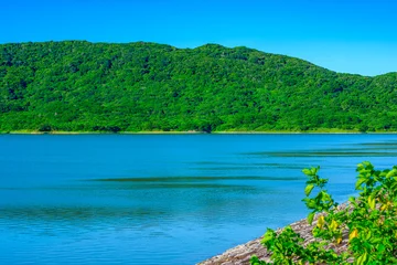 Fototapete Grün 青く穏やかな湖面と深い緑の山々が広がる石垣島底原ダムの美しい風景  © Masahiro.Hamanaka