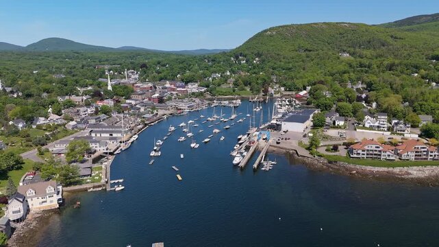 Numerous boats and historic schooners rest in the calm blue waters of Camden Harbor under a clear summer sky. Maine, USA. June 2, 2024. 