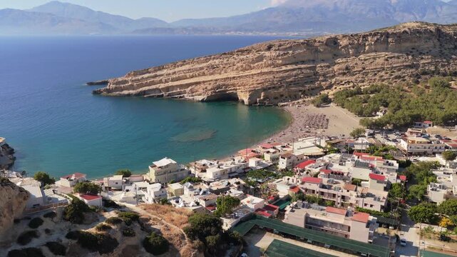 Aerial drone view of Matala bay with its sandy beach and the famous cave cliff, Matala, Greece