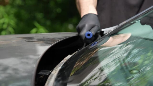 Auto glass removal 4K footage pulling cut out wire through sealant. Technician pulling a cutting wire along the windshield frame to separate auto glass from the vehicle body