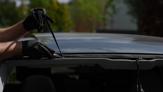 Windshield Adhesive Removal 4k video. Technician uses blade to remove old sealant from vehicle frame. Essential prep for secure glass bonding