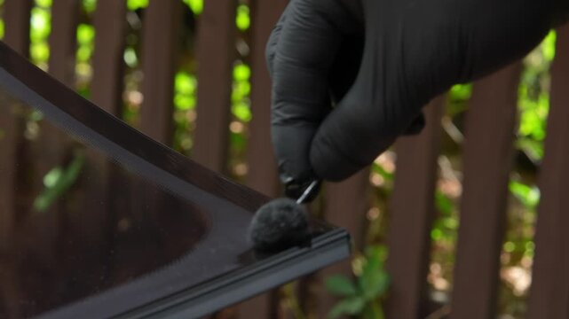 Automotive glass installation prepping new windshield with primer 4K. Applying black bonding primer to a replacement windshield mounted on suction cups before vehicle installation