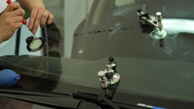 Repairing a broken car window in 4K. Close up of a sharp pick tool checking the impact zone of an auto windshield for potential crack propagation