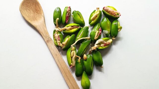 Germinated green paterna seeds of Inga jinicuil arranged in a heart shape next to a bamboo spoon for typical dish from Guatemala