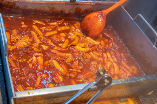 Spicy rice cake tteokbokki cooking in a metal pan at traditional street food market in south korea.