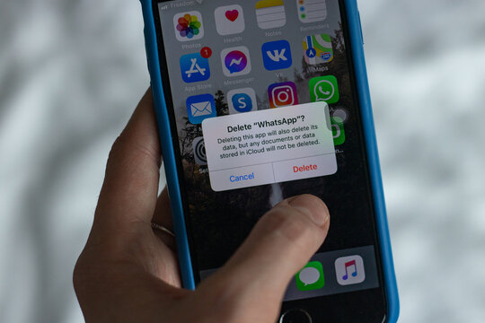 A woman is trying to delele WhatsApp from her phone. Choice concept. Selective focus
