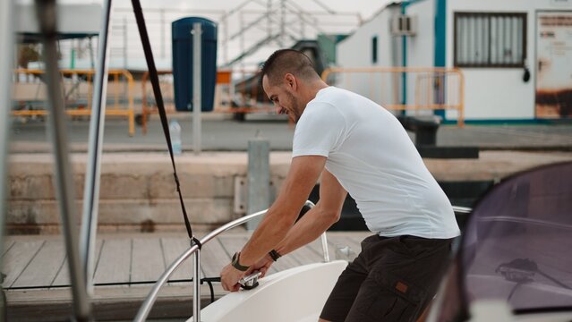 Man tying a rope on a boat at a marina before setting sail