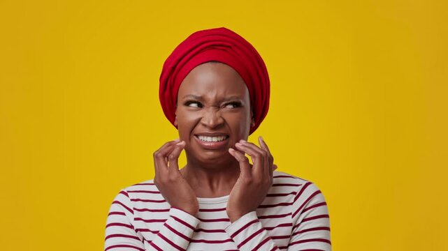Worried Black Woman In Her 30s Touching Face With Concern At Studio Against Bright Yellow Background, Expressing Distress Or Discomfort. Capturing Emotion In Portrait, Focus On Feelings.