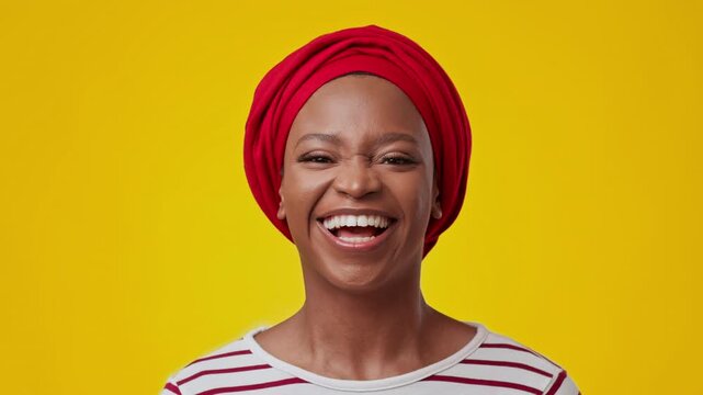Joyful Expression. Smiling Black Woman In Bright Head Wrap Displaying Happiness At Studio With Yellow Background. Celebrating Positivity And Confidence In Vibrant Environment.