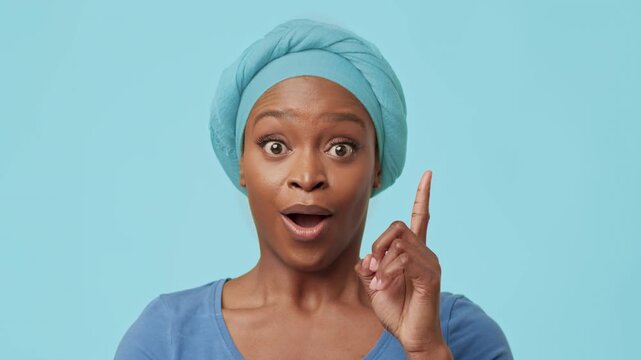Surprised Young Black Woman With Turban Looking Off Camera With Shocked Expression, Enjoying Moment Of Joy At Home. Playful And Lighthearted Atmosphere Enhancing Overall Vibe.