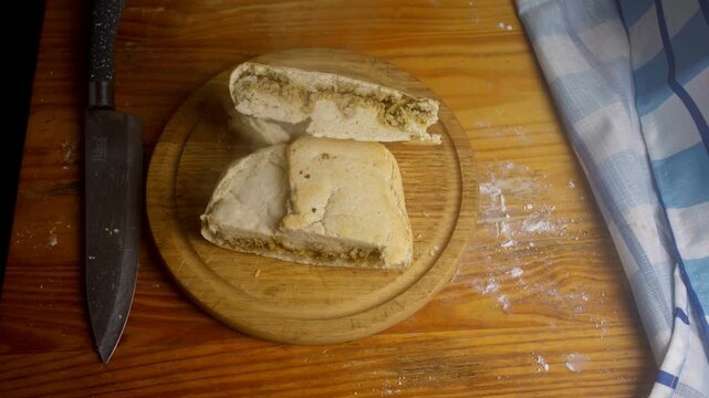 Close up of rustic meat-filled pastry next to a chef knife on a kitchen table