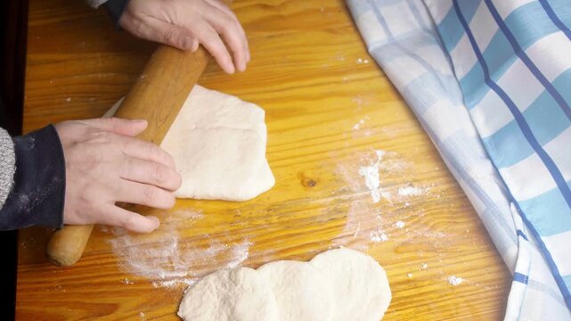Close up of rolling out raw pastry dough on a rustic wooden table