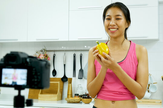 Asian influencer vlogger live review healthy lifestyle at home kitchen. Young woman blogger vlog happy lifestyle eating vegetables fruit vegan product. Healthy smile women social media vlogger live