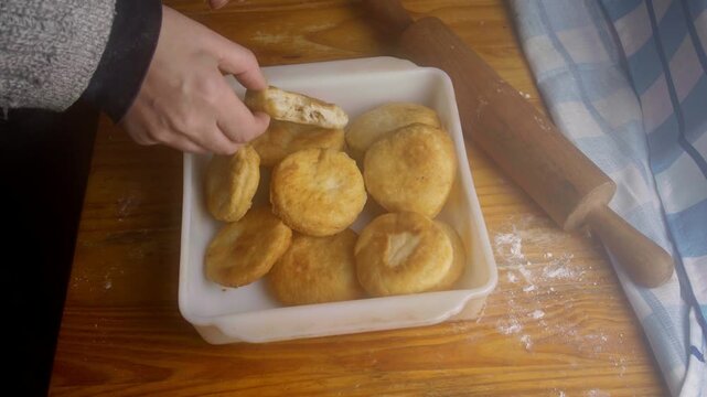 Top view of person placing a broken piece of a fresh sopaipilla back into a container